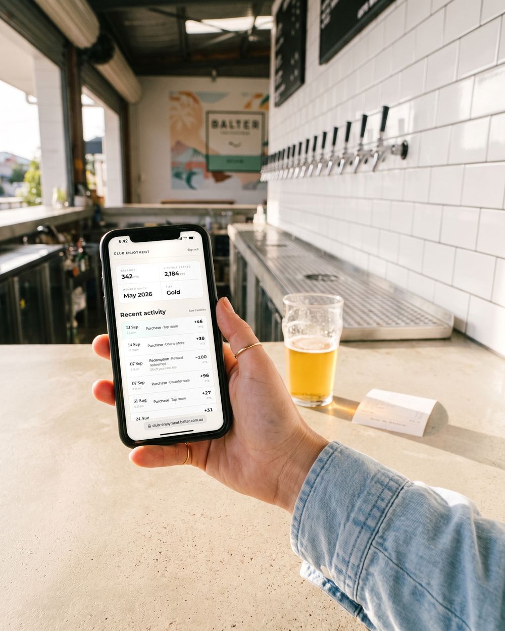 At the bar, Sarah checks her Club Enjoyment activity: plus 46 points from the tap room