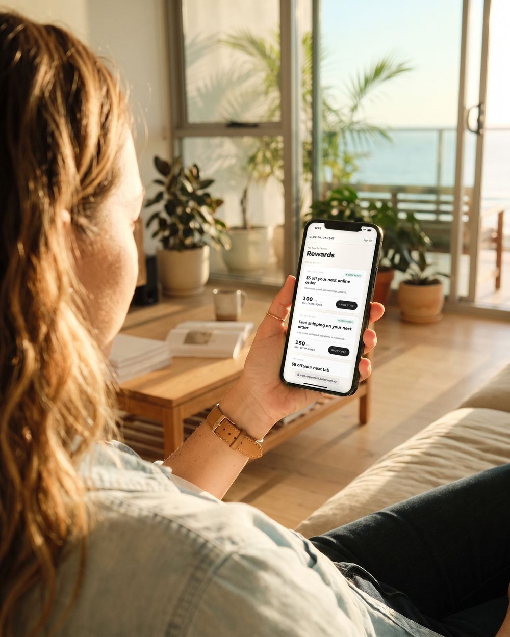 On her sofa at home, Sarah opens Rewards: her $5-off code is ready
